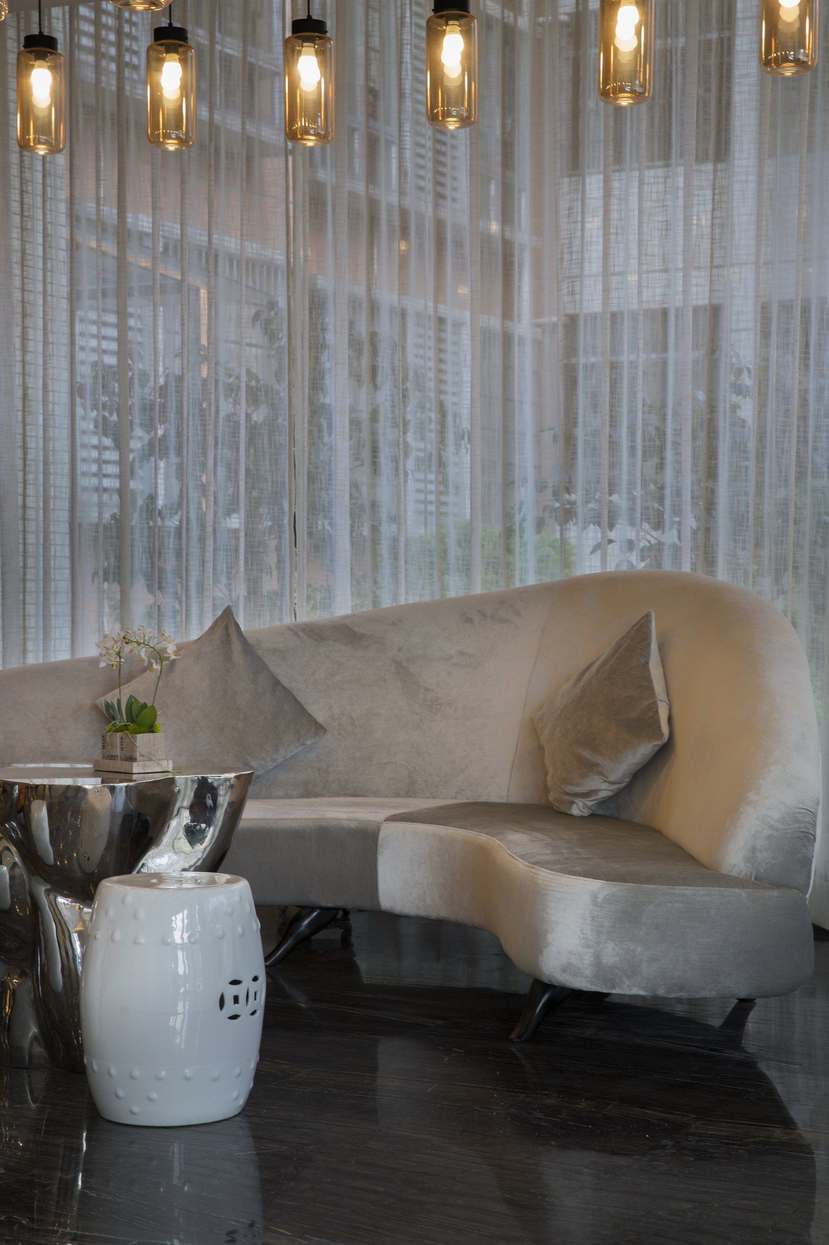 A modern living room with a grey sofa, a metallic coffee table, and a white vase with flowers.