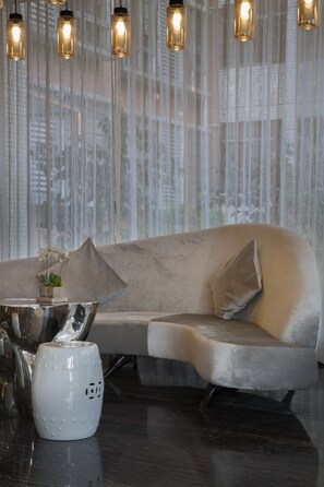 Una sala de estar moderna con un sofá gris, una mesa de centro metálica y un jarrón blanco con flores.