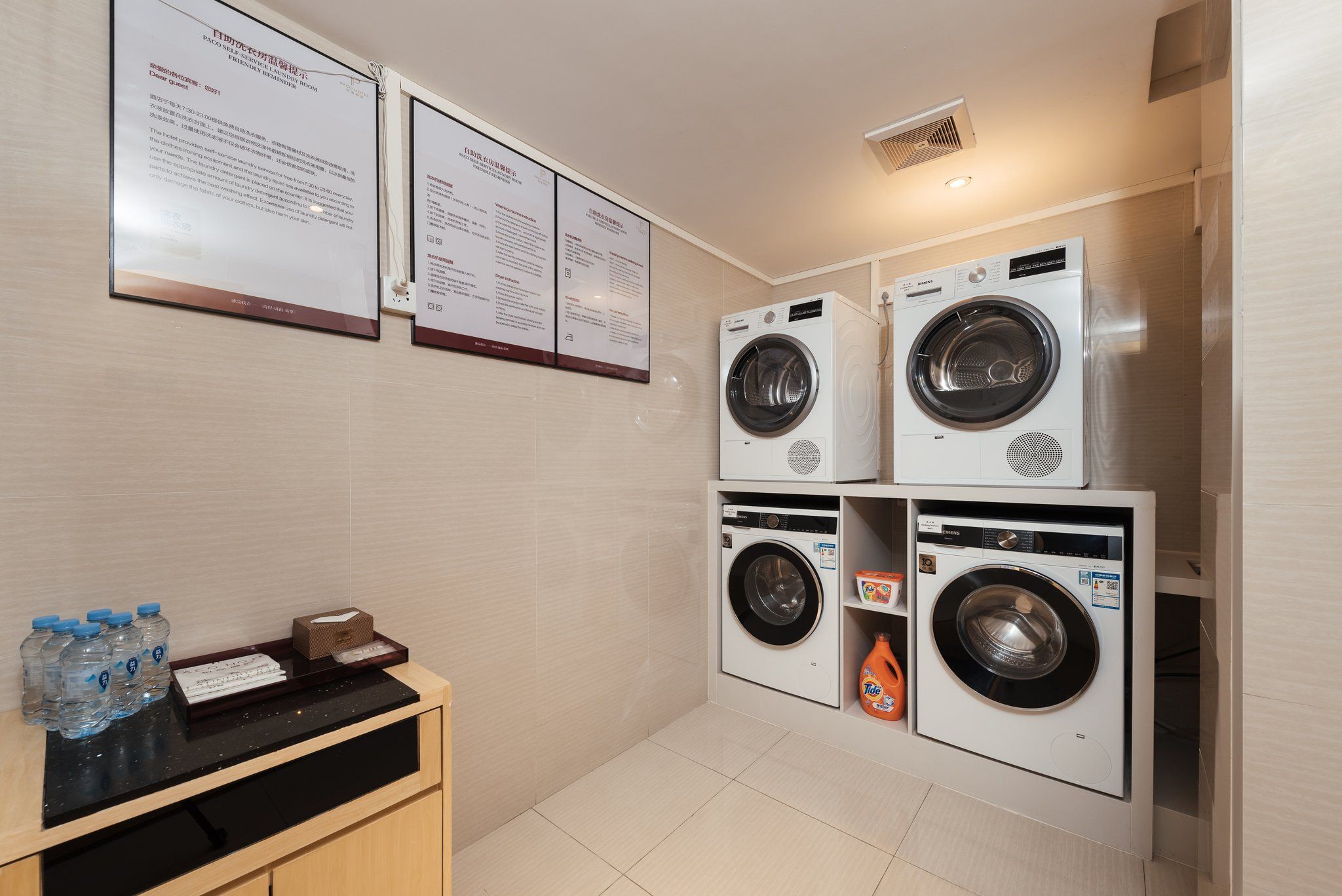 A laundry room with four washing machines, a water dispenser, and a tissue box on a counter.