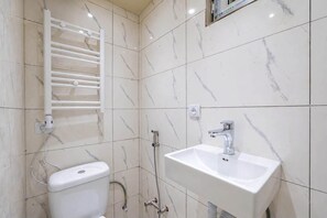 Un bany amb vàter, un lavabo, una dutxa i una barra de tovalloles.