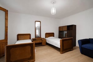 Una habitació amb dos llits de fusta, un armari, un mirall i una làmpada penjant.