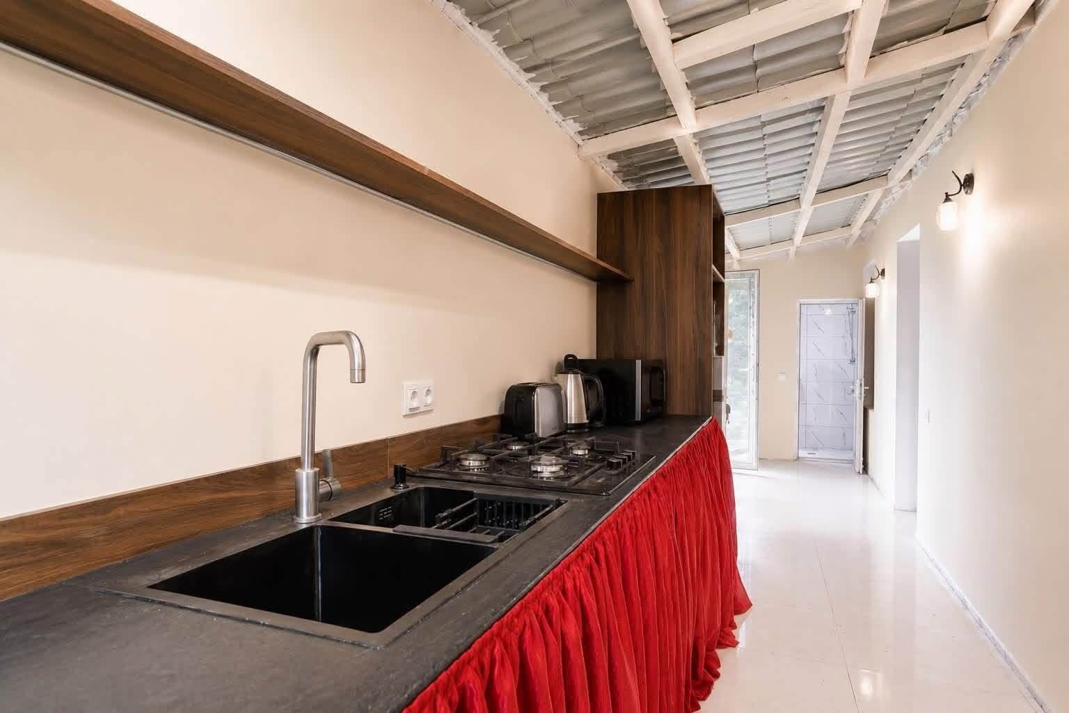 A modern kitchen with a stainless steel sink, a gas stove, and a red countertop.