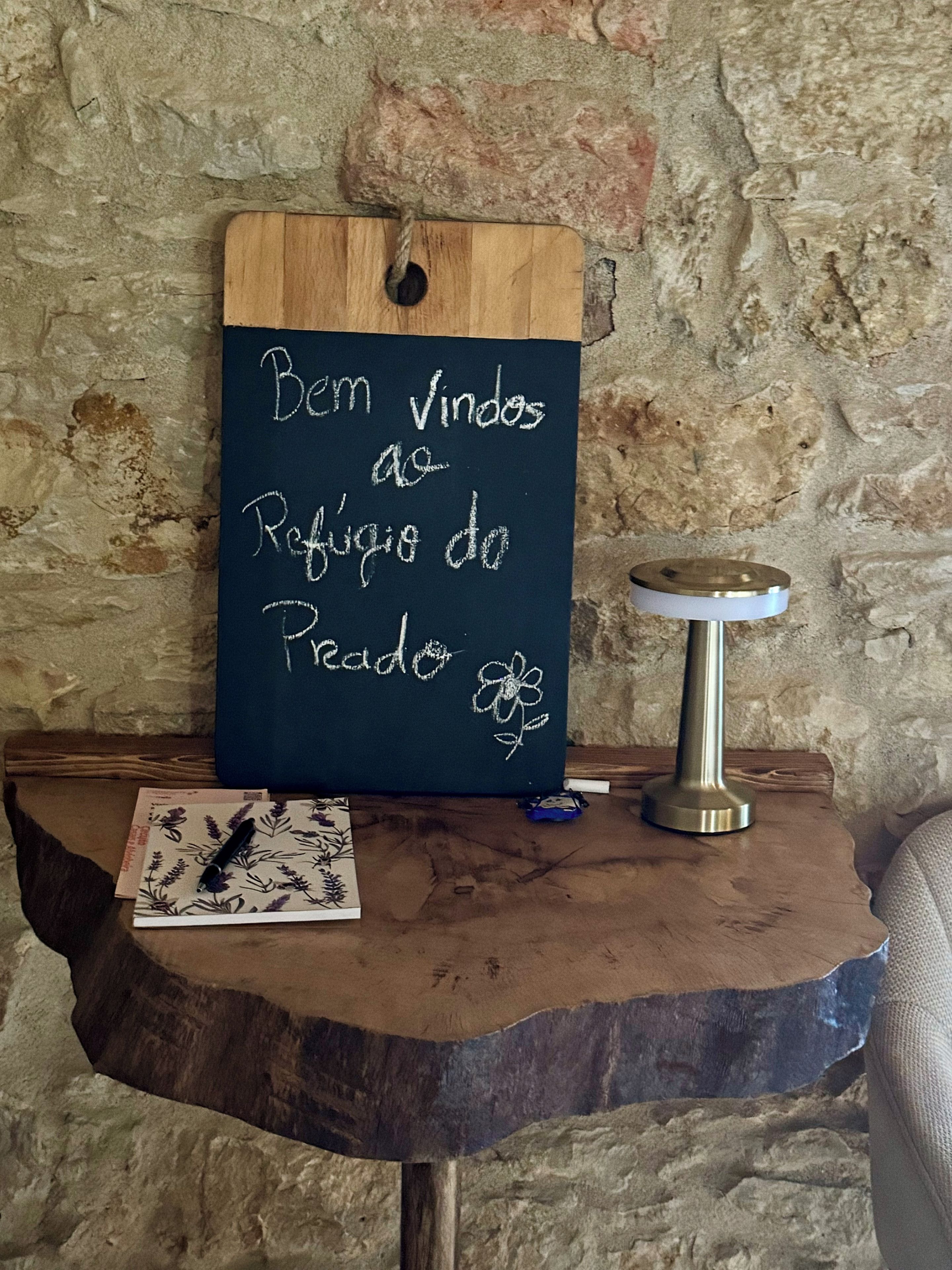 Una pizarra con un mensaje, una mesita con una vela y un objeto decorativo.