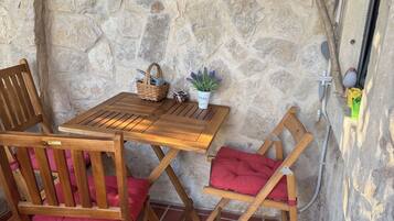 Un muro de piedra con una mesa y sillas de madera, una pequeña planta en maceta y un adorno.