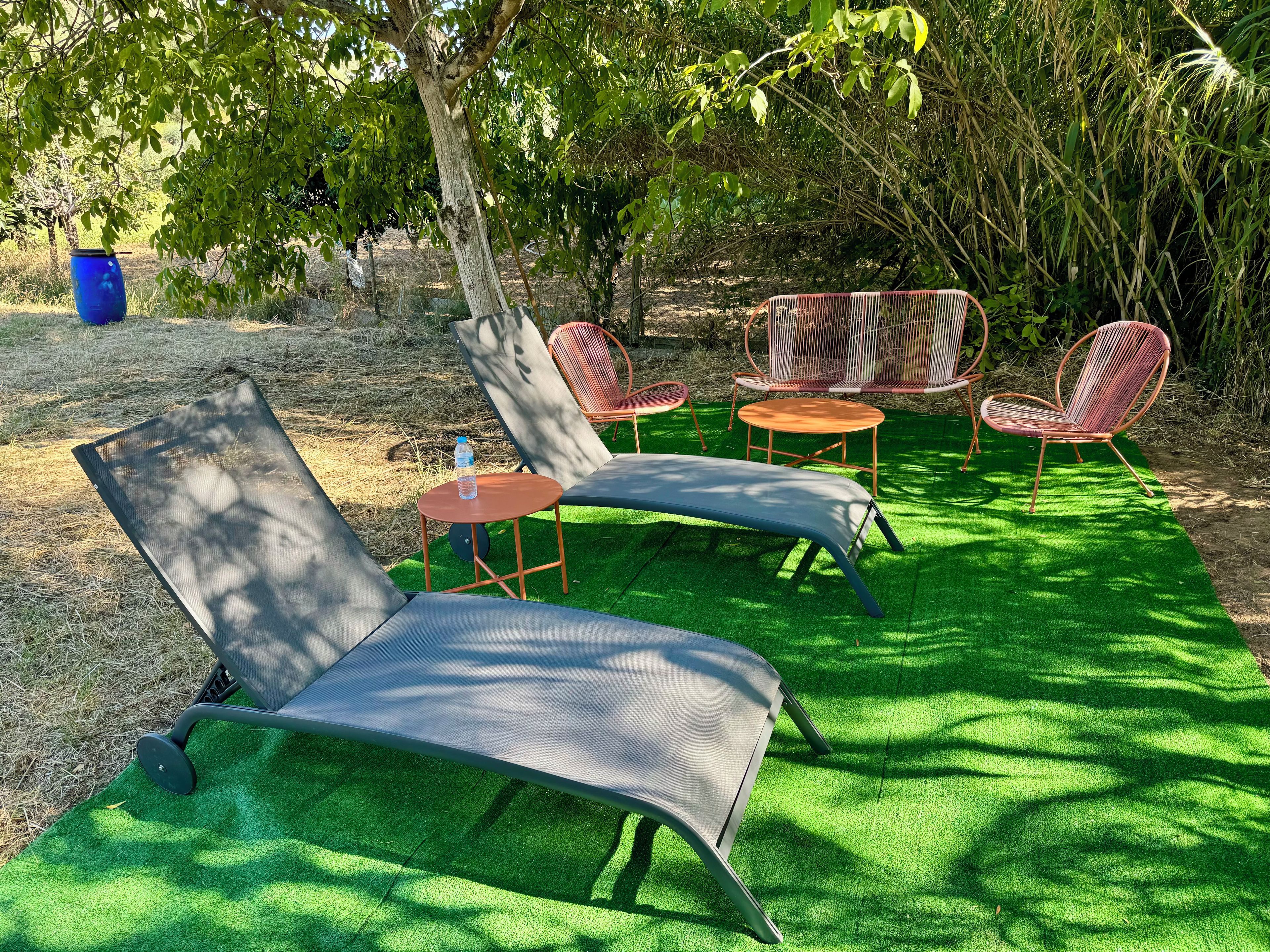 A garden area with outdoor furniture including a lounge chair, a small round table, and two chairs.