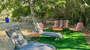 A garden area with outdoor furniture including a lounge chair, a small round table, and two chairs.