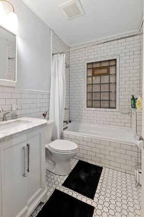 A bathroom with a white bathtub, a toilet, and a shower curtain. - Lakewood Park Main Floor, Free parking (Lakewood)