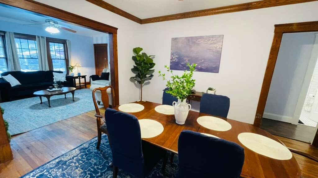 A dining area with a wooden table, blue chairs, and a vase with green plants.