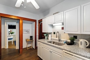 A modern kitchen with white cabinets, a granite countertop, and stainless steel appliances.
