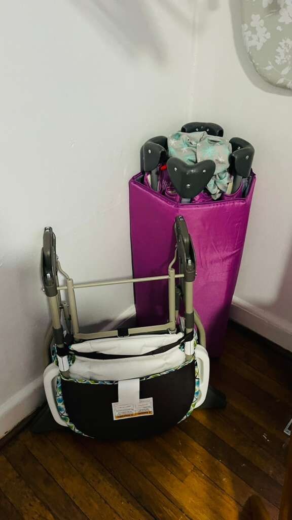 A wheelchair in a corner with a purple storage bin behind it.