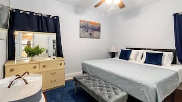Ein Schlafzimmer mit Bett, Schminktisch, einer Bank, einem Deckenventilator und einem Bild an der Wand.