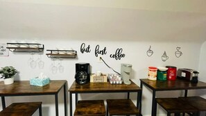 Een café met tafels, stoelen, koffiezetapparatuur en wanddecoraties.