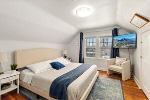 A bedroom with a bed, bedside tables, a TV, a chair, and a window with a view. - Lakewood Park Top Floor, Free parking (Lakewood)