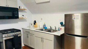 Une cuisine équipée d’une cuisinière, d’un four à micro-ondes, d’un évier et d’un réfrigérateur.