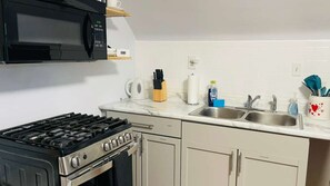 A kitchen with a stove, microwave, sink, and cabinets.