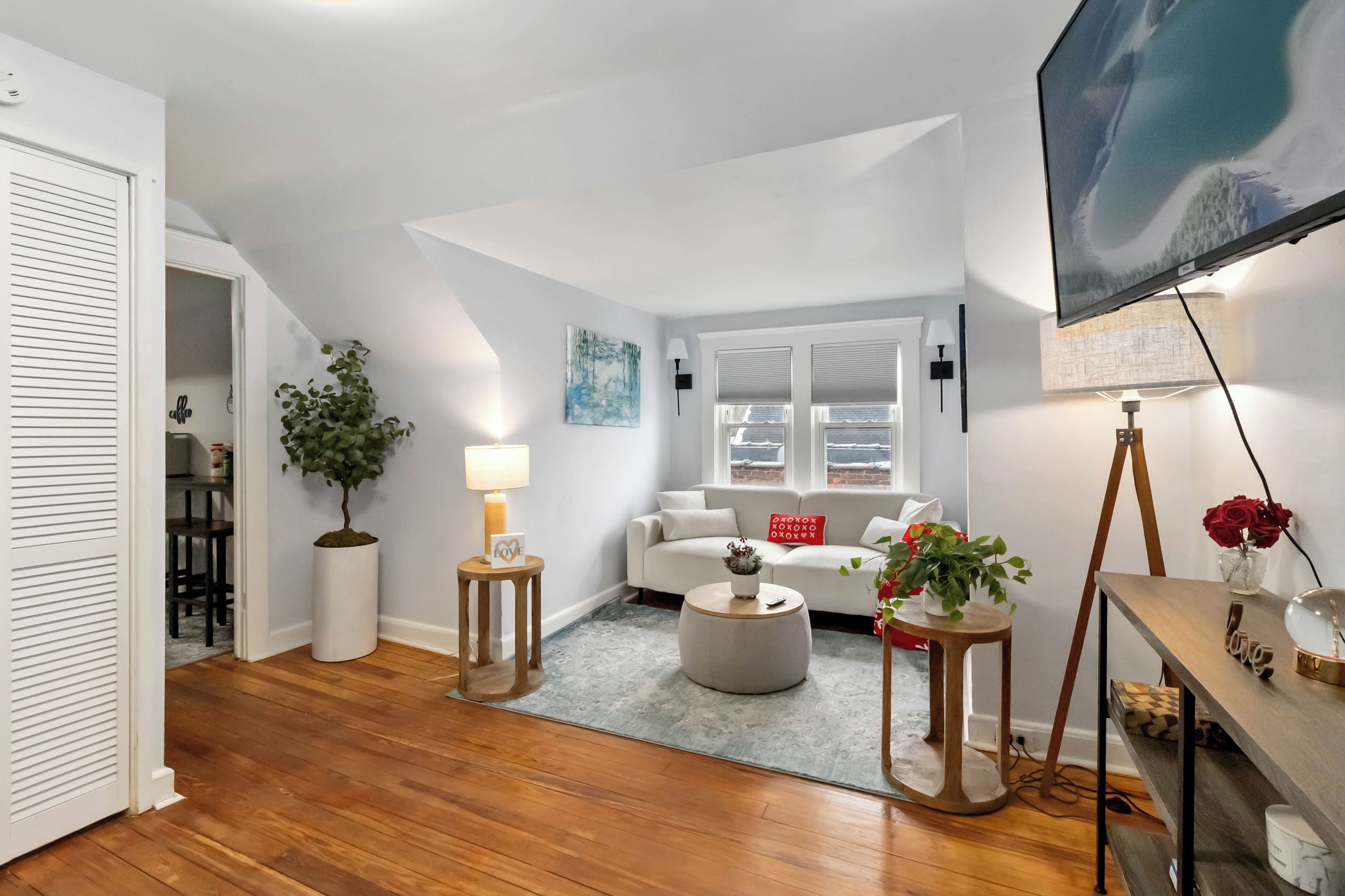 A modern living room with a sofa, coffee table, and a TV mounted on the wall.