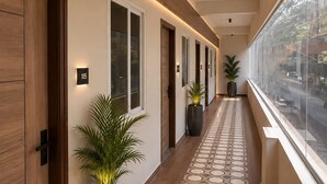 A hallway with wooden doors, numbered signs, potted plants, and patterned floor tiles. - Petals Suites & Hotels (Bengaluru)