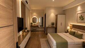 A modern bedroom with a bed, bedside tables, a TV, and a mirror. - Petals Suites & Hotels (Bengaluru)