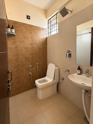 A modern bathroom with a toilet, shower, and sink. - Petals Suites & Hotels (Bengaluru)