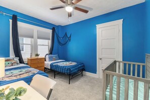 A bedroom with a blue wall, a ceiling fan, a bed with Star Wars themed bedding, a nightstand, a dresser, and a crib. - ✨ Family-Friendly Charm in the Heart of Lakewood 🌿<br>Steps from Parks, Trails & Lake Views<br>Welcome to your serene escape in Lakewood—where convenience meets charm in one of Cleveland’s most walkable neighborhoods. (Lakewood)