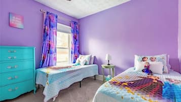 A bedroom with two beds, a dresser, a window with curtains, and a wall with a poster.