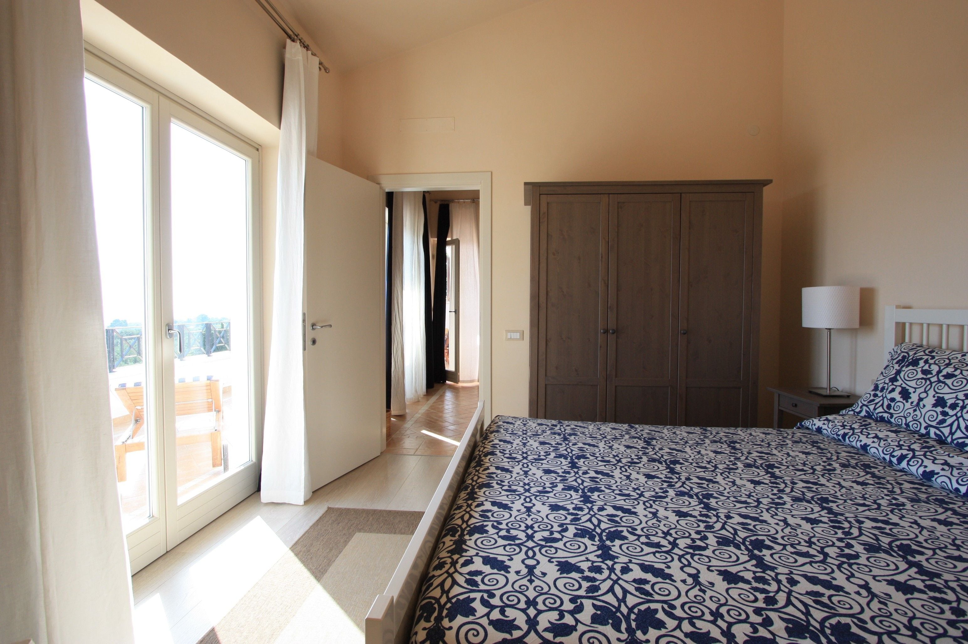 Une chambre à coucher avec un lit, une armoire et une salle de bain visible à travers une porte ouverte.
