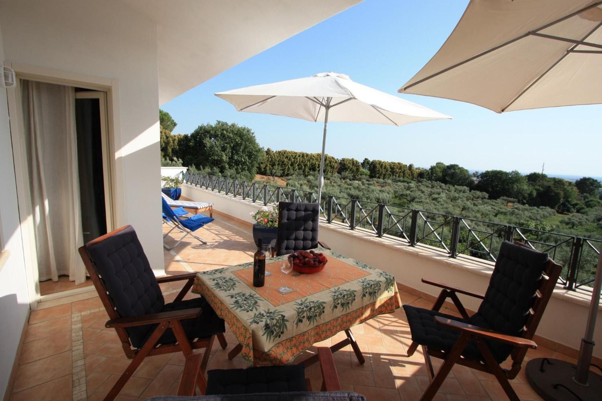 Une terrasse extérieure avec une table, des chaises et un grand parasol.