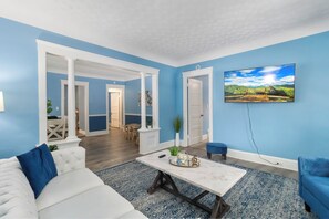 A living room with a white sofa, a blue armchair, a coffee table, and a painting on the wall. - ✨ Family-Friendly Charm in the Heart of Lakewood 🌿<br>Steps from Parks, Trails & Lake Views<br>Welcome to your serene escape in Lakewood—where convenience meets charm in one of Cleveland’s most walkable neighborhoods. (Lakewood)