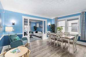 A modern living room with a blue wall, a dining area with a wooden table and chairs, and a separate seating area with a white sofa. - ✨ Family-Friendly Charm in the Heart of Lakewood 🌿<br>Steps from Parks, Trails & Lake Views<br>Welcome to your serene escape in Lakewood—where convenience meets charm in one of Cleveland’s most walkable neighborhoods. (Lakewood)
