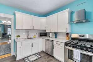 Een moderne keuken met witte kastjes, een roestvrijstalen fornuis en een magnetron.