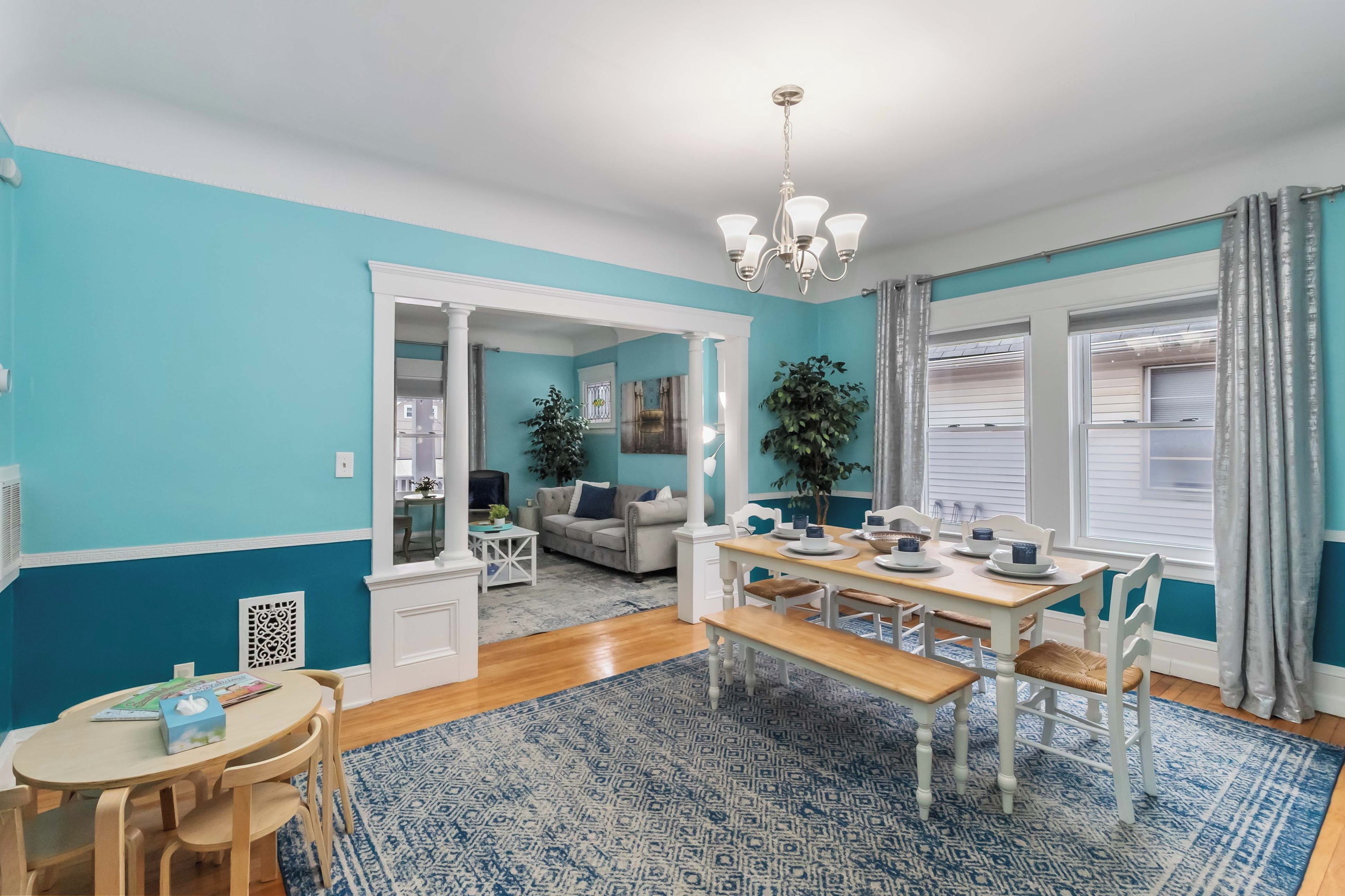 A dining area with a wooden table, chairs, and a blue patterned rug.