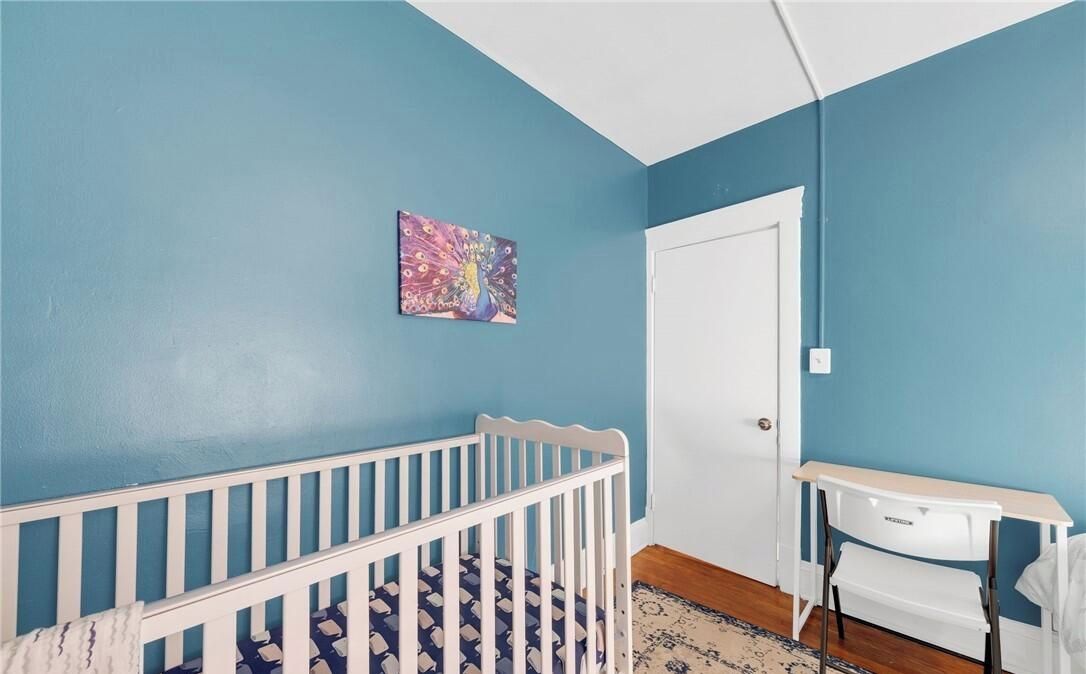 A room with a blue wall, a white door, a crib, and a small white table.