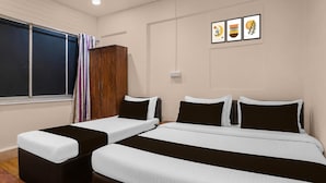 A hotel room with two single beds and a double bed, a wardrobe, a window with curtains, and three framed artworks on the wall. - Classic Santacruz Metro Station (Mumbai)