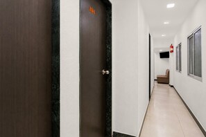 A hallway with a door marked '104' leading to a room with a bed and a television. - Classic Santacruz Metro Station (Mumbai)