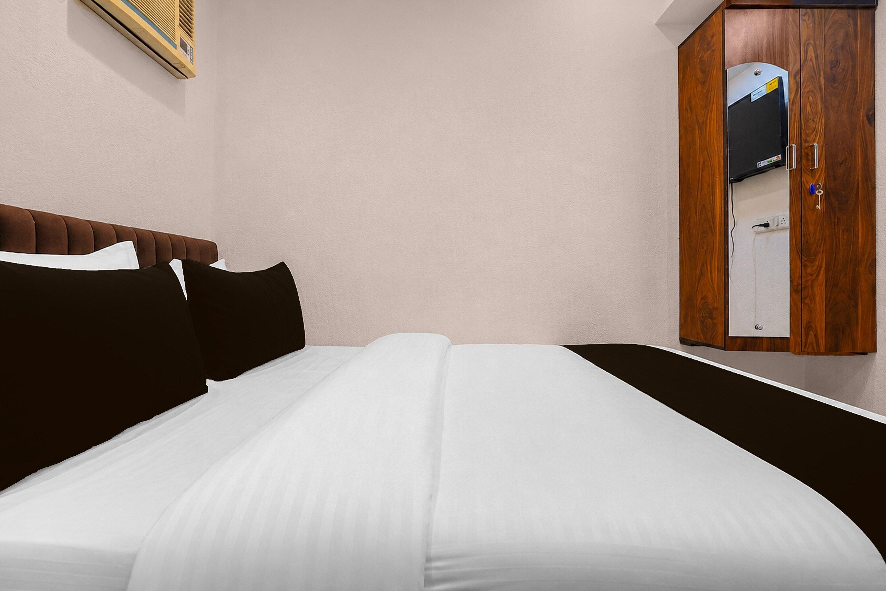 A neatly made bed with white sheets and black pillows in a hotel room.