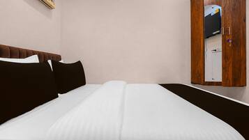 A neatly made bed with white sheets and black pillows in a hotel room.