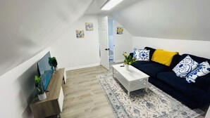 Ett modernt vardagsrum med en soffa, ett soffbord och en tv som står på ett träställ.