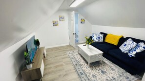 A modern living room with a sofa, coffee table, and a TV on a wooden stand. - Cleveland Tiny Hideaway- Free Parking (Cleveland)