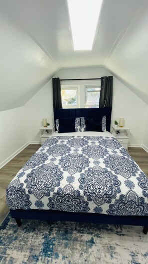 A bedroom with a bed, two bedside tables, a window, and a skylight. - Cleveland Tiny Hideaway- Free Parking (Cleveland)