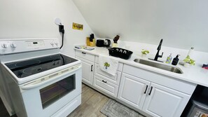A kitchen with white cabinets, a stove, a sink, and various kitchen items. - Cleveland Tiny Hideaway- Free Parking (Cleveland)