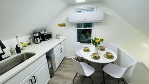 A small kitchenette with a microwave, coffee maker, and sink. There is a dining area with a table set for two and a vase with flowers. - Cleveland Tiny Hideaway- Free Parking (Cleveland)