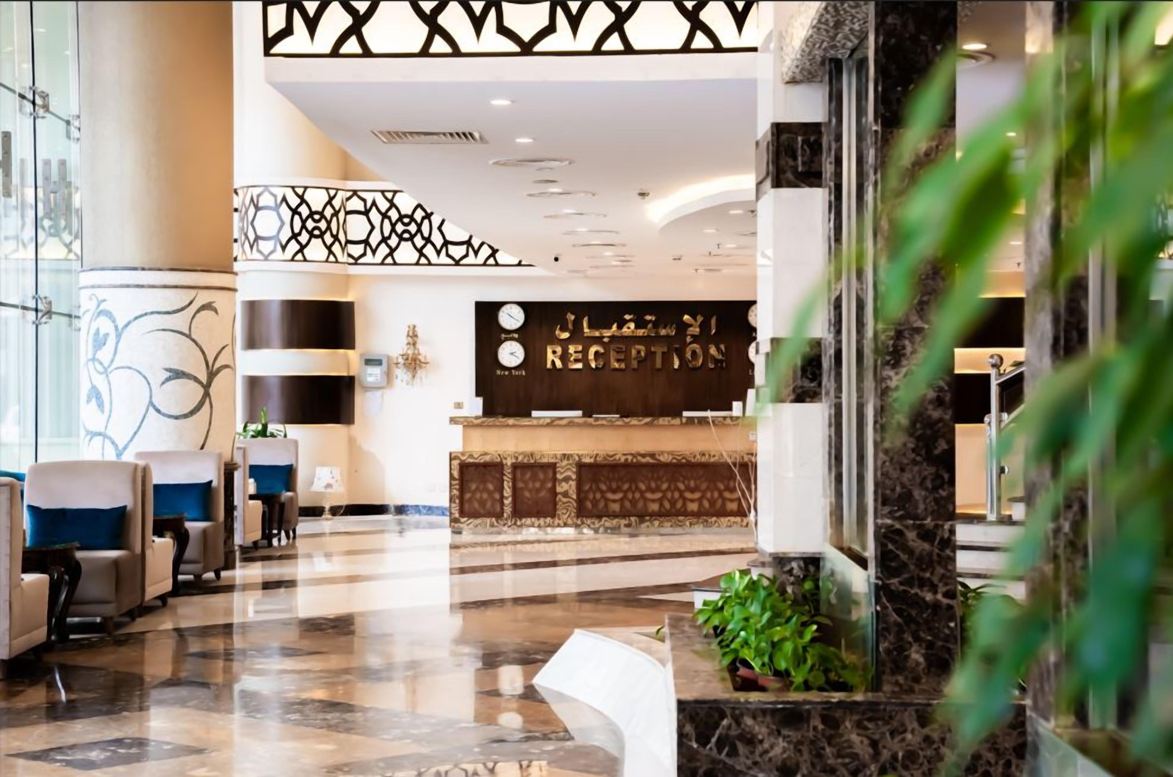 A hotel reception area with a reception desk, seating area, and decorative elements.