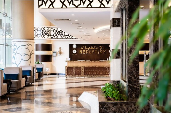 Un'area reception di un hotel con scrivania, zona salotto e elementi decorativi.