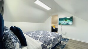 A bedroom with a bed, a TV mounted on the wall, and a ceiling light. - CLE Tiny Hideaway- Free Parking (Cleveland)