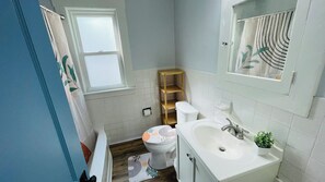 A bathroom with a toilet, sink, and a wooden shelf unit. - Brand new Apartment in West Cleveland (Cleveland)