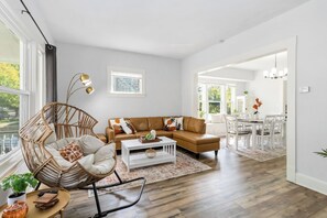 A modern living room with a brown leather sofa, a wicker chair, and a white coffee table. - Brand new Apartment in West Cleveland (Cleveland)