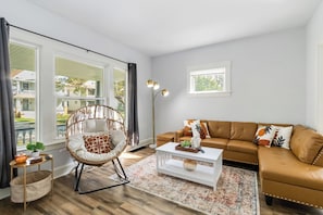 Ein Wohnzimmer mit Sofa, Sessel, Couchtisch und Stehlampe.