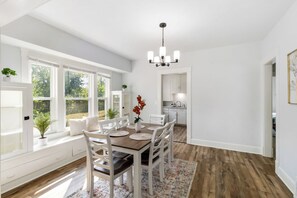 A dining area with a wooden table, white chairs, and a chandelier. - Brand new Apartment in West Cleveland (Cleveland)