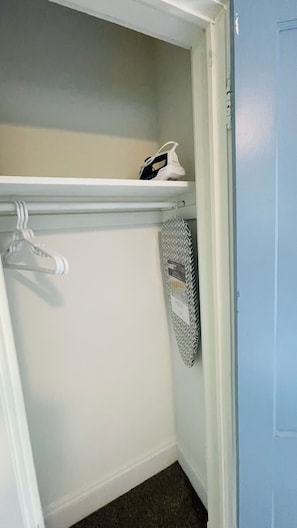Ein Kleiderschrank mit Kleiderstange, Ablagefläche und einem gefalteten Kleidungsstück.