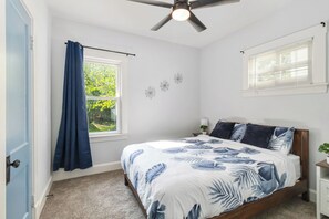 A bedroom with a bed, a ceiling fan, a window with curtains, and a small bedside table with a lamp. - Brand new Apartment in West Cleveland (Cleveland)